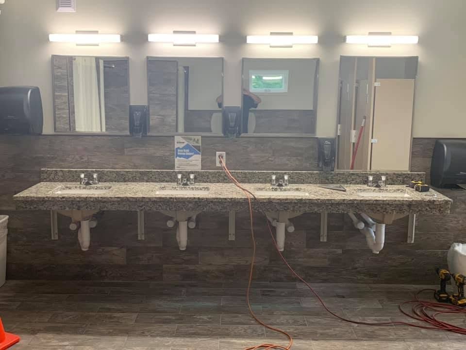 Four-sink vanity with new white PVC drains and P-traps under a granite countertop